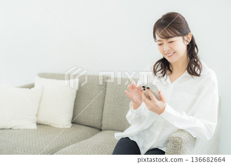 一個女人在客廳裡看著她的智能手機 一個女人在客廳裡看著她的智能手機 136682664