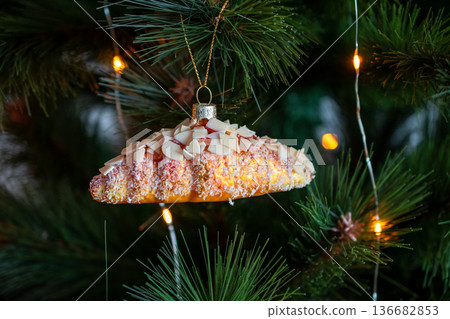 Festive Croissant Ornament Hanging on a Decorated Christmas Tree Festive Croissant Ornament Hanging on a Decorated Christmas Tree 136682853
