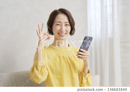 Woman making an OK sign in the living room Woman making an OK sign in the living room 136683849