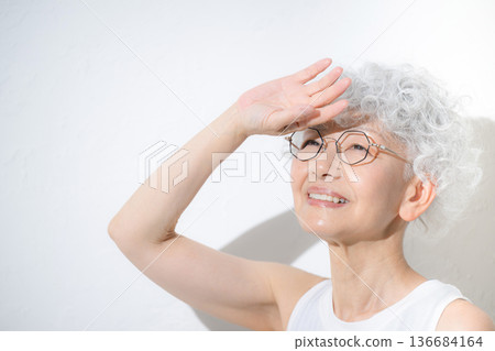 Close-up of a cheerful gray-haired senior woman in sleeveless sportswear looking up 136684164