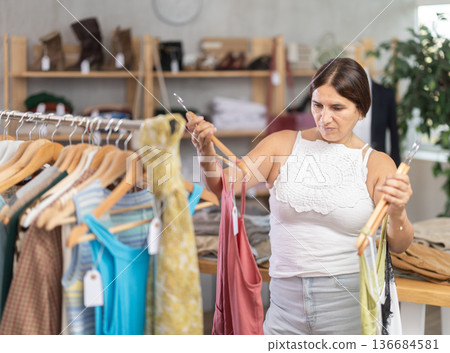 Latin woman customer turn over and choose something summer cloth in store, 136684581