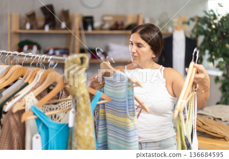 Latin woman customer turn over and choose something summer cloth in store, 136684595