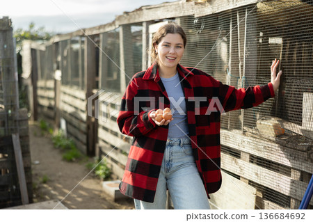 Young woman holding fresh eggs in chicken coop 136684692