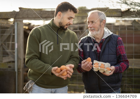Man with senior father presents farms eco-friendly products - chicken eggs Man with senior father presents farms eco-friendly products - chicken eggs 136684709