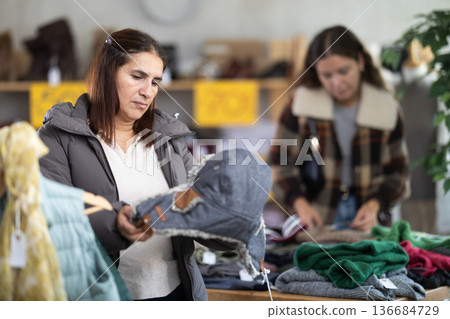 Adult woman choosing fur hat in clothing store 136684729