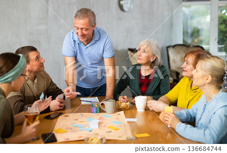 Happy elderly man playing board game with friends Happy elderly man playing board game with friends 136684744