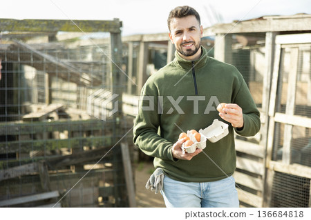 Positive man stands and holds in hands palms few fresh chicken eggs Positive man stands and holds in hands palms few fresh chicken eggs 136684818