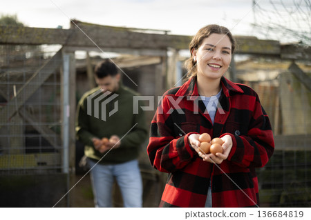 Young woman holding fresh eggs in chicken coop 136684819