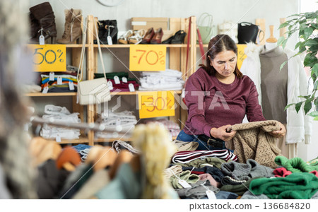 Adult woman chooses sweater in clothing store 136684820