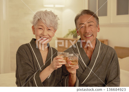 Senior couple drinking whiskey in the bedroom, portrait, looking at camera Senior couple drinking whiskey in the bedroom, portrait, looking at camera 136684923