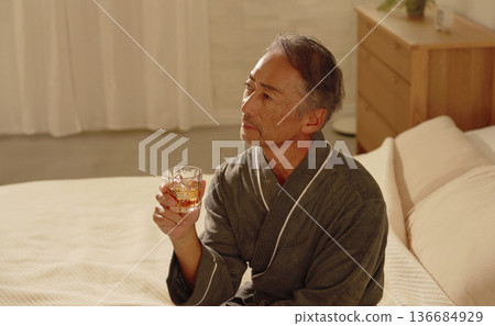 一位老年男子在臥室裡喝威士忌 136684929