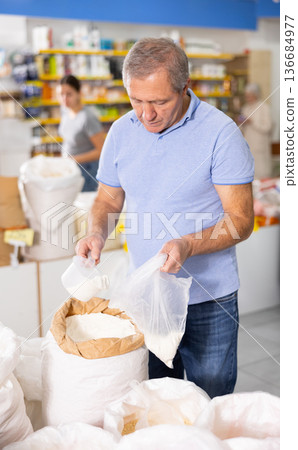 Elderly man filling polybag with wheat flour in grocery store 136684977