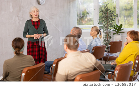 Elderly female tutor teaching group of mature students 136685017