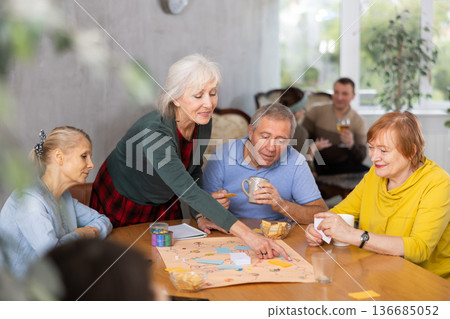 Elderly woman playing board game with friends at table 136685052