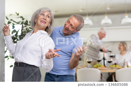 Party people celebrating friendship. Four mature friends dancing and singing at home. Cheerful women and men enjoy music together 136685086