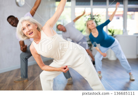 Active mature men and women practicing Jazz-funk dance in training hall 136685111