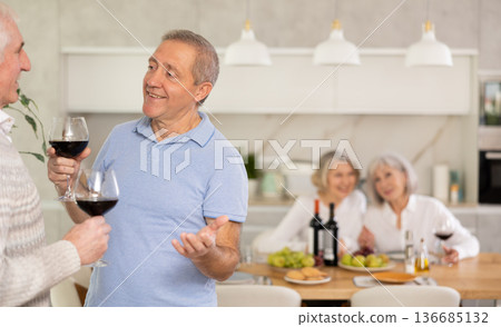 Elderly men drink red wine and tell each other news during festive dinner at home Elderly men drink red wine and tell each other news during festive dinner at home 136685132