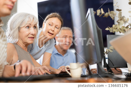Woman teacher helping elderly people learn how to use computer Woman teacher helping elderly people learn how to use computer 136685176