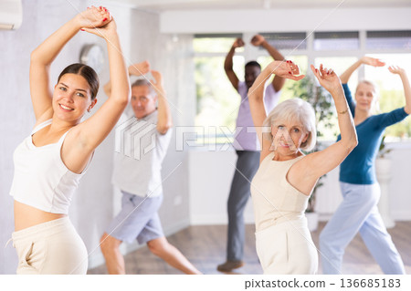 Female instructor teaches senior students of different ages basic movements of contemporary dances Female instructor teaches senior students of different ages basic movements of contemporary dances 136685183