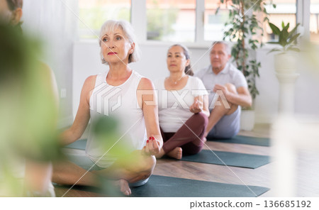 Women of different years doing yoga on mat in fitness studio 136685192