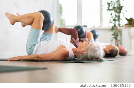 People lying on karemat, pulled bent legs to themselves and clamped soft-ball in knee People lying on karemat, pulled bent legs to themselves and clamped soft-ball in knee 136685193