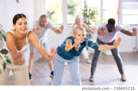Female instructor teaches senior students of different ages basic movements of contemporary dances Female instructor teaches senior students of different ages basic movements of contemporary dances 136685218
