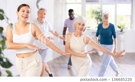 Men and women of different ages practicing Hip-hop dance in training hall 136685220