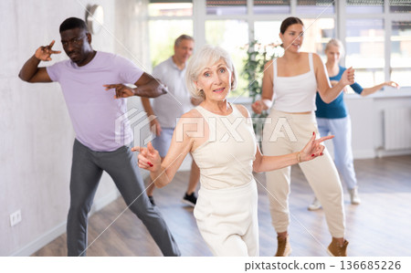 Men and women of different ages practicing Rock 'n' Roll dance in training hall 136685226
