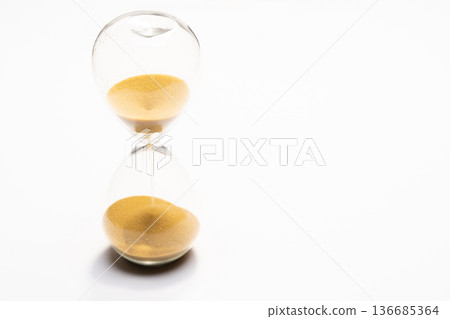 Close-up of an hourglass with golden sand falling 136685364
