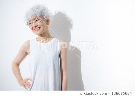 一位笑容可掬的灰髮老婦人穿著夏季運動服或瑜珈服，抬頭仰望。 136685694