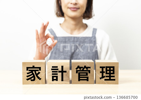 A woman wearing an apron and a block with the words "household management" written on it A woman wearing an apron and a block with the words "household management" written on it 136685700