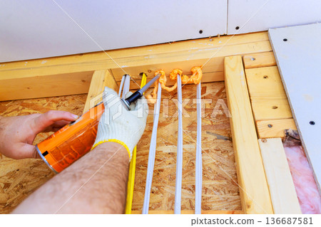 Construction worker uses fire proof sealant to secure materials in building project Construction worker uses fire proof sealant to secure materials in building project 136687581