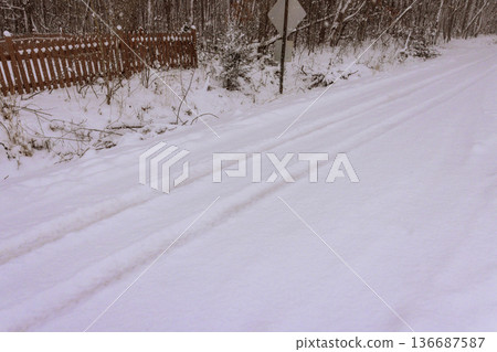 Snow covers quiet road in forest area during winter time in early morning hours Snow covers quiet road in forest area during winter time in early morning hours 136687587