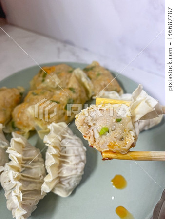 Korean dumplings filled with a mix of savory ingredients like ground meat, tofu, and vegetables. Mandu can be steamed, boiled, or pan-fried, making it a versatile and delicious snack or meal. 136687787