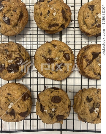 Freshly baked cookies with a golden-brown finish and chocolate chips. Perfectly crisp on the edges with a soft center, offering a delicious, comforting treat for any occasion. 136688104