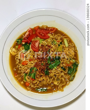 Indomie goreng, a popular Indonesian instant noodle dish, stir-fried to perfection with a blend of savory seasonings. Often served with fried egg, crispy shallots, and vegetables for flavor Indomie goreng, a popular Indonesian instant noodle dish, stir-fried to perfection with a blend of savory seasonings. Often served with fried egg, crispy shallots, and vegetables for flavor 136688324