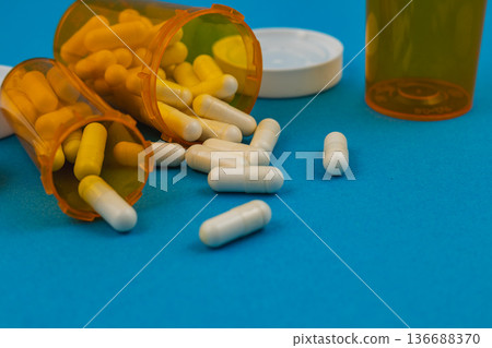 Pills spill from orange containers on blue surface Pills spill from orange containers on blue surface 136688370