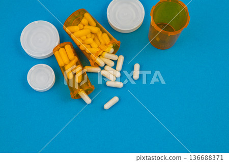 Pill bottles open on blue background with capsules spilled out Pill bottles open on blue background with capsules spilled out 136688371