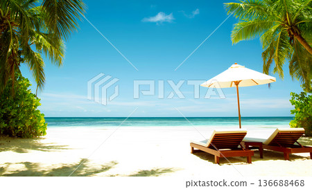 idyllic tropical scene with two wooden sun loungers and a white umbrella on fine sand, set in front of a crystal turquoise sea under a bright blue sky 136688468