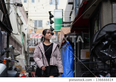 一位年輕女子走在東京一條充滿復古氣息的商業街上。 一位年輕女子走在東京一條充滿復古氣息的商業街上。 136688814