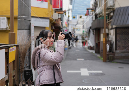 Young woman taking a photo of a retro shopping street in Tokyo 136688828