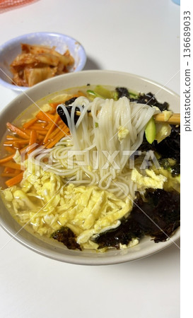 Janchi Guksu, a light and savory Korean noodle dish served in a clear broth, topped with vegetables, egg strips, and seaweed. A simple yet flavorful meal often enjoyed on special occasions. 136689033