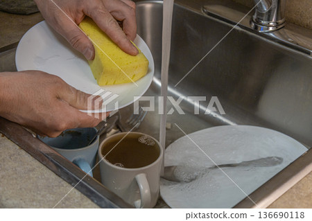 Washing Dishes With Sponge Under Tap 136690118