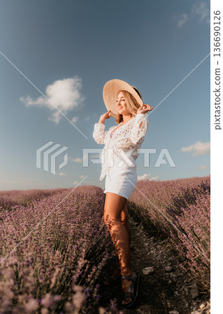 Lavender woman straw hat standing in a blooming field under a blue summer sky with plenty of copy space Lavender woman straw hat standing in a blooming field under a blue summer sky with plenty of copy space 136690126