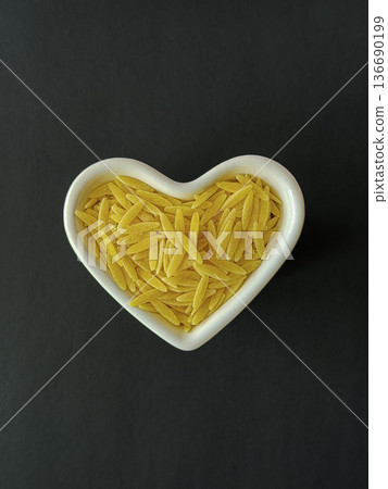 Orzo Pasta in Heart Shaped Bowl on Dark Background Orzo Pasta in Heart Shaped Bowl on Dark Background 136690199
