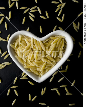 Orzo Pasta in Heart Shaped Bowl on Dark Background 136690200