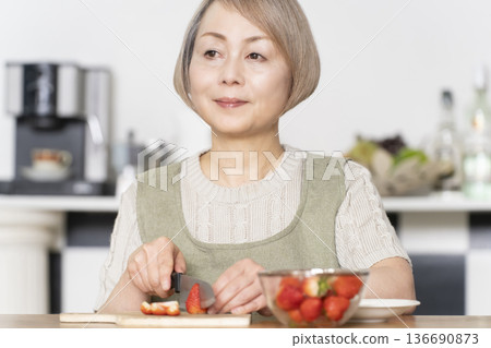 Cut strawberries in the dining kitchen and make a yogurt dessert. 136690873