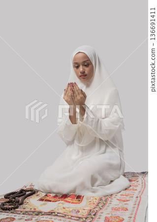 An indoor setting portrays woman in traditional attire immersed in personal prayer and meditation An indoor setting portrays woman in traditional attire immersed in personal prayer and meditation 136691411