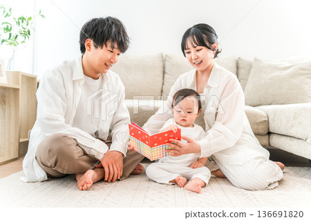 A family of parenting generation reading a picture book to their child or baby in the living room of their home (childcare, parenting, skinship) A family of parenting generation reading a picture book to their child or baby in the living room of their home (childcare, parenting, skinship) 136691820