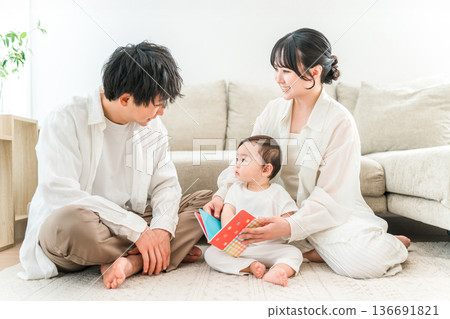 A family of parenting generation reading a picture book to their child or baby in the living room of their home (childcare, parenting, skinship) 136691821